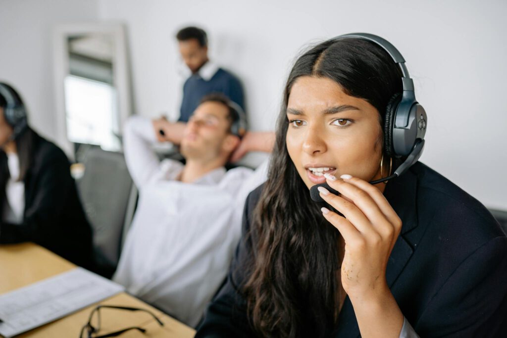 Close-up of a woman working in a call center, wearing a headset, focused on her task.