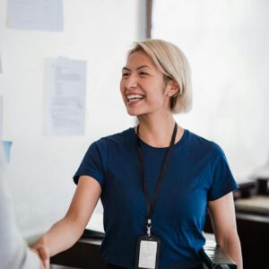 Friendly businesswoman in a blue shirt shaking hands during meeting, radiating professionalism and approachability.