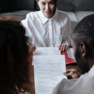 Three people reviewing documents in an office setting, focusing on adoption paperwork.